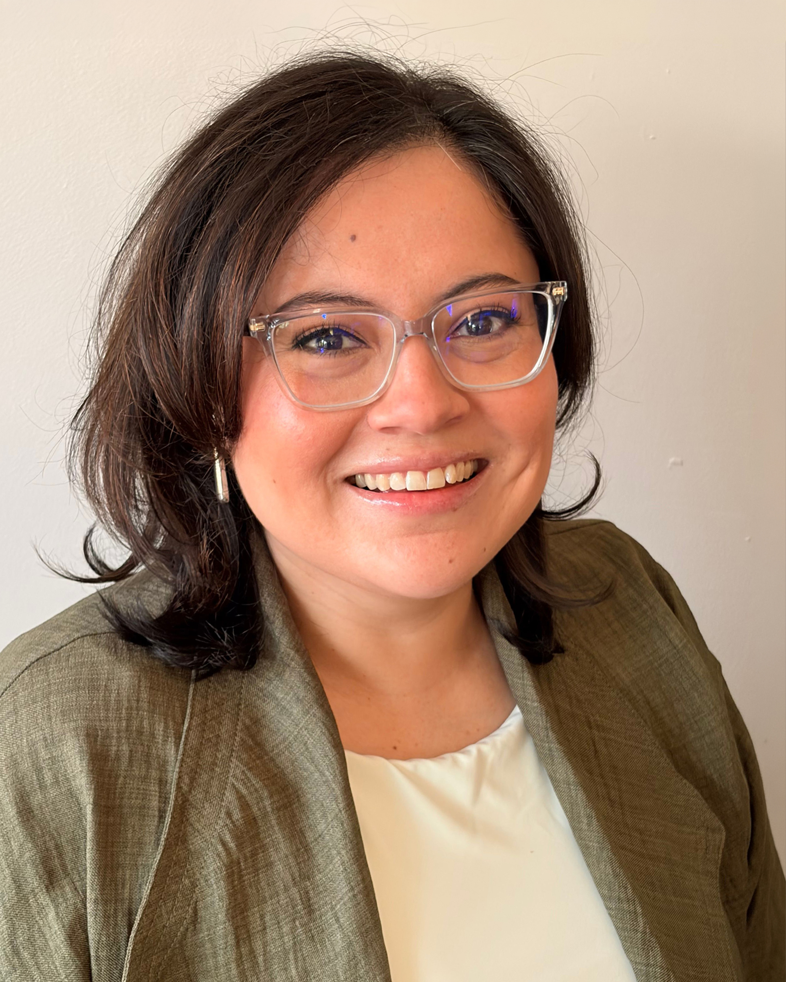 Original source photograph of the woman wearing glasses and an olive blazer